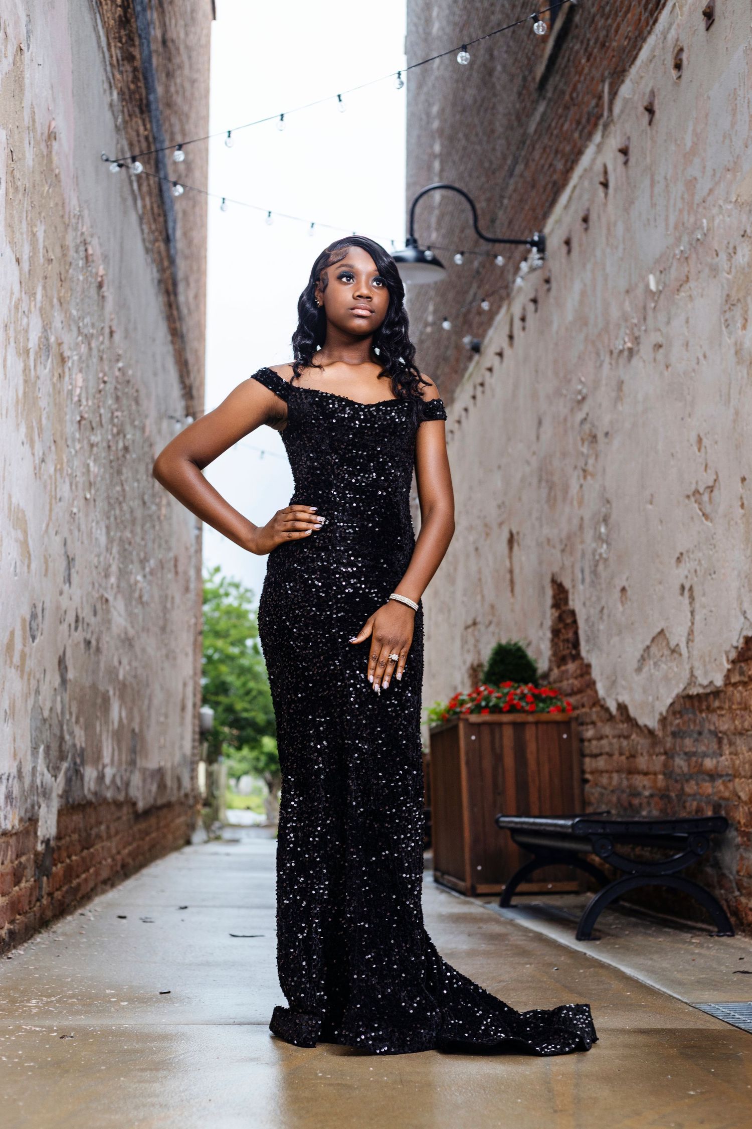 Elegant black evening gown photos taken in rustic industrial setting with exposed brick walls.