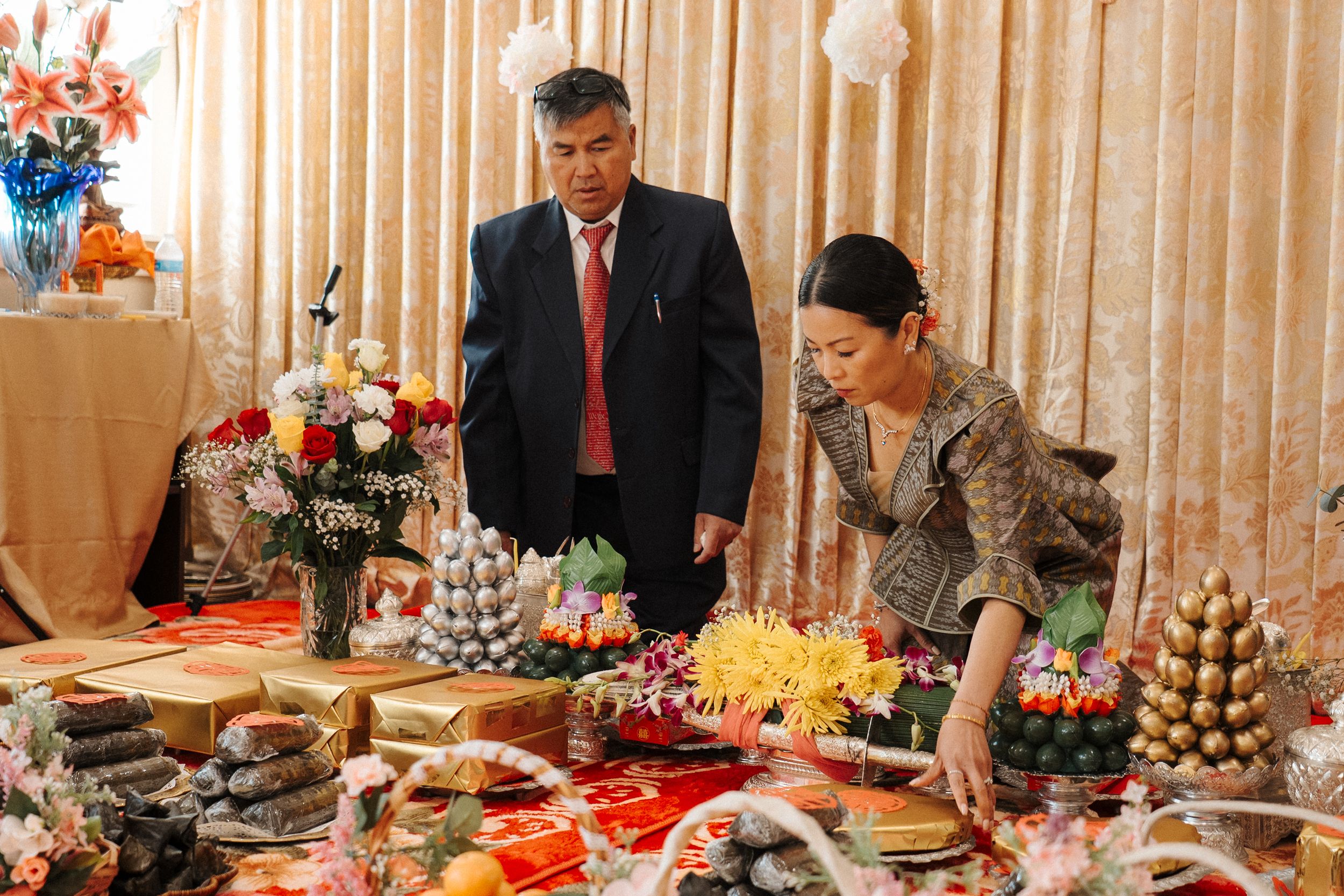 Beautifully decorated banquet table with colorful desserts and floral arrangements at a traditional Asian celebration.
