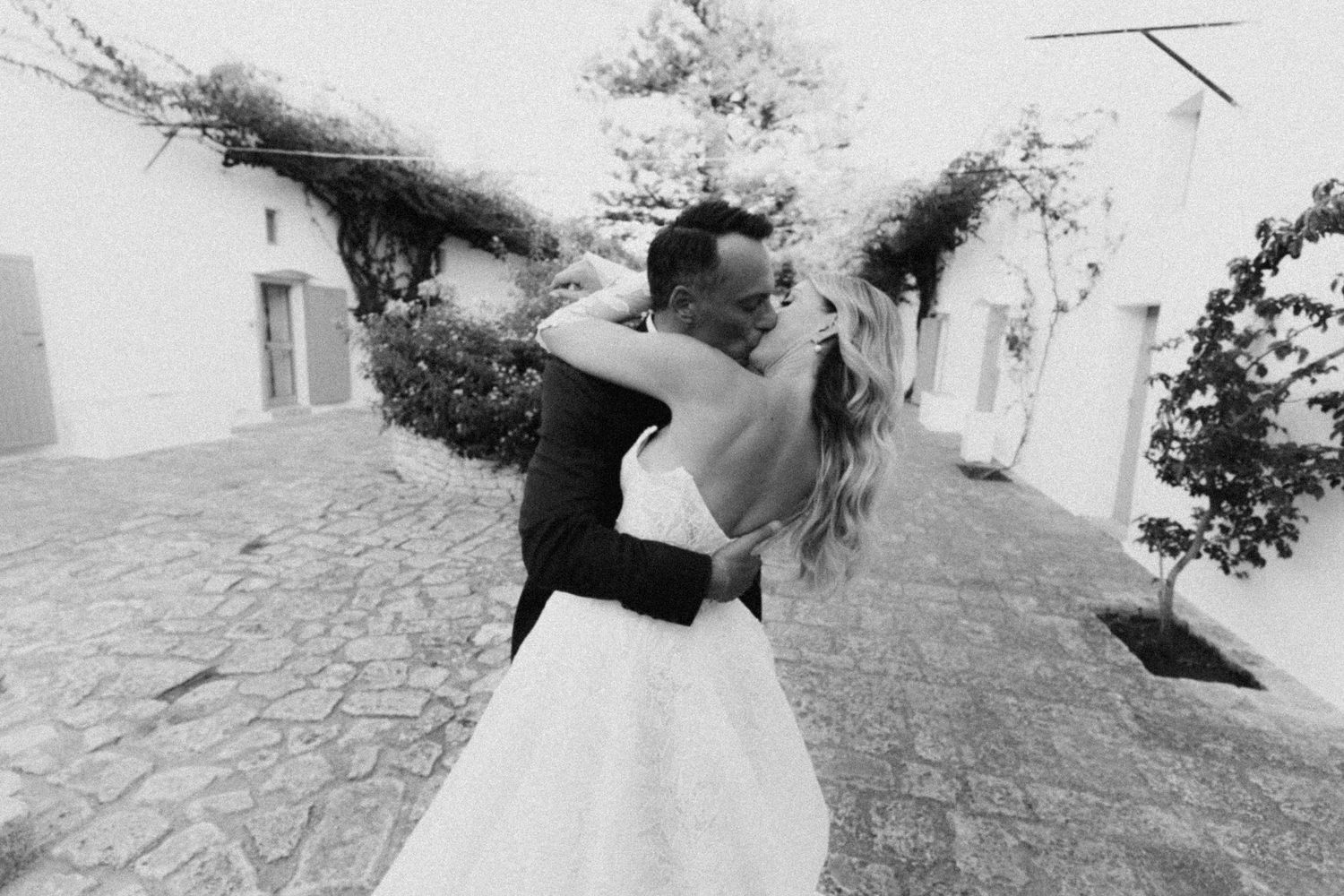 A black and white photo collage showing romantic wedding moments in outdoor settings near stone walls.