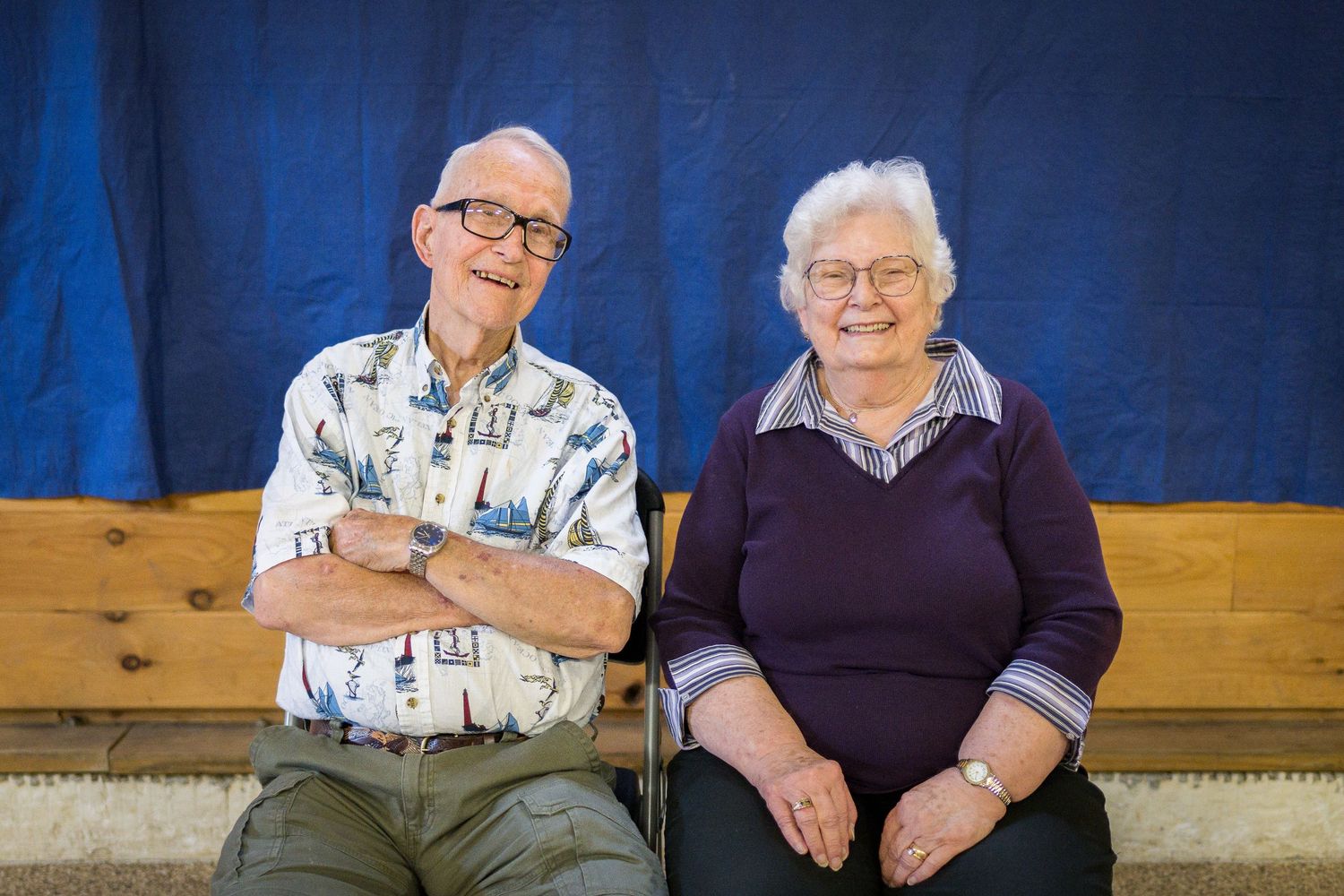 People sitting together on a wooden bench in a blue-lit room.