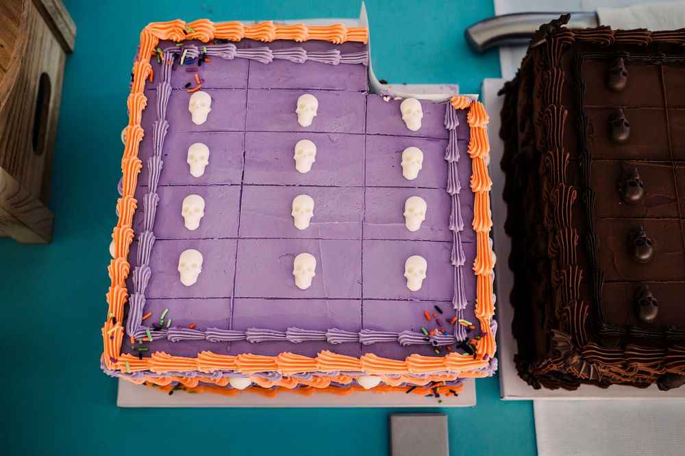 A purple frosted sheet cake decorated with white ghost designs and orange border.