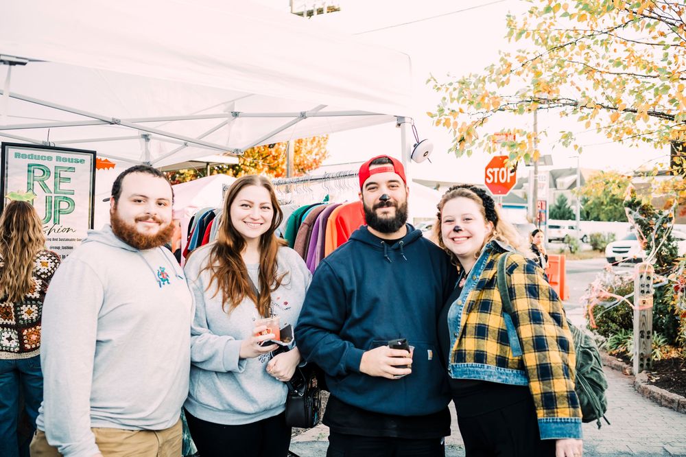 Friends smiling and laughing together at an outdoor fall festival.