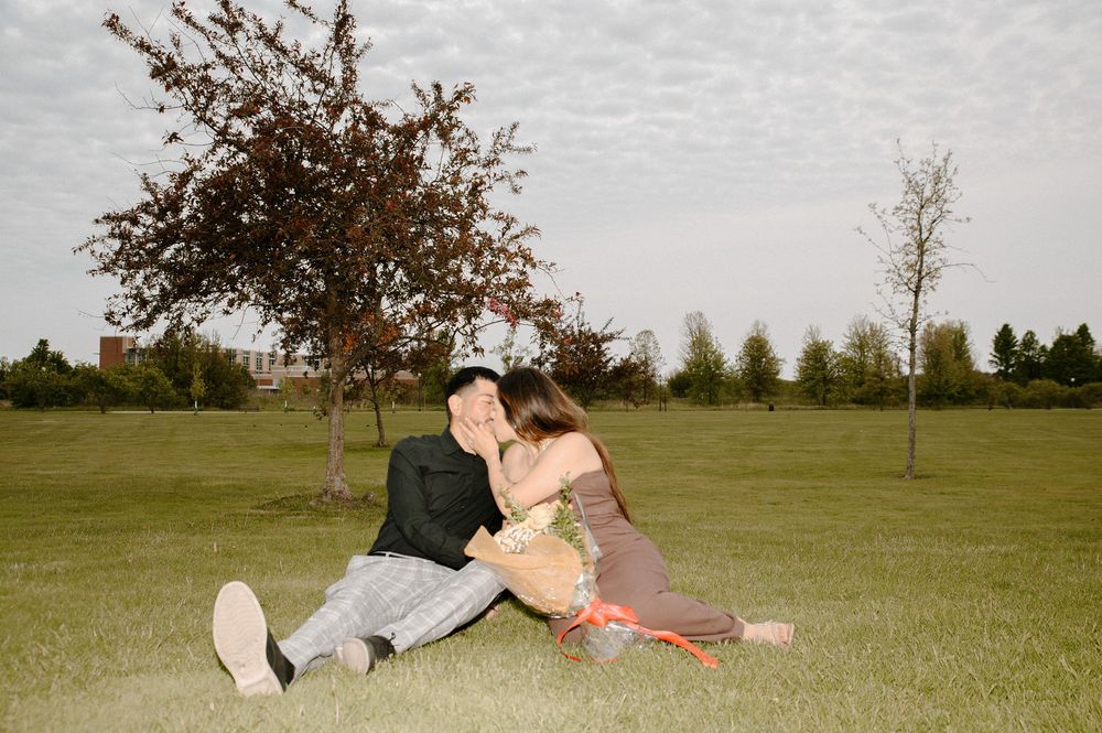 A couple lies in the grass during a romantic outdoor moment.