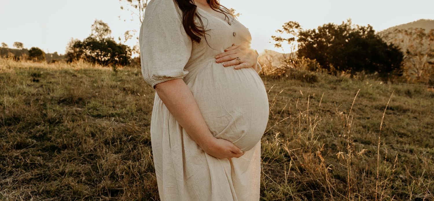 Collection of sunset maternity photos showing tender moments with pregnant belly on grassy hillside in warm golden light.