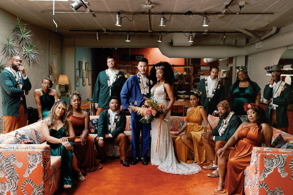 Wedding party group portrait in eclectic venue with bride in white and colorful bridesmaids.