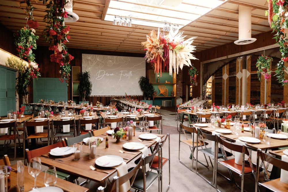 Elegant wedding reception hall with long tables, hanging greenery, and star-shaped chandelier.