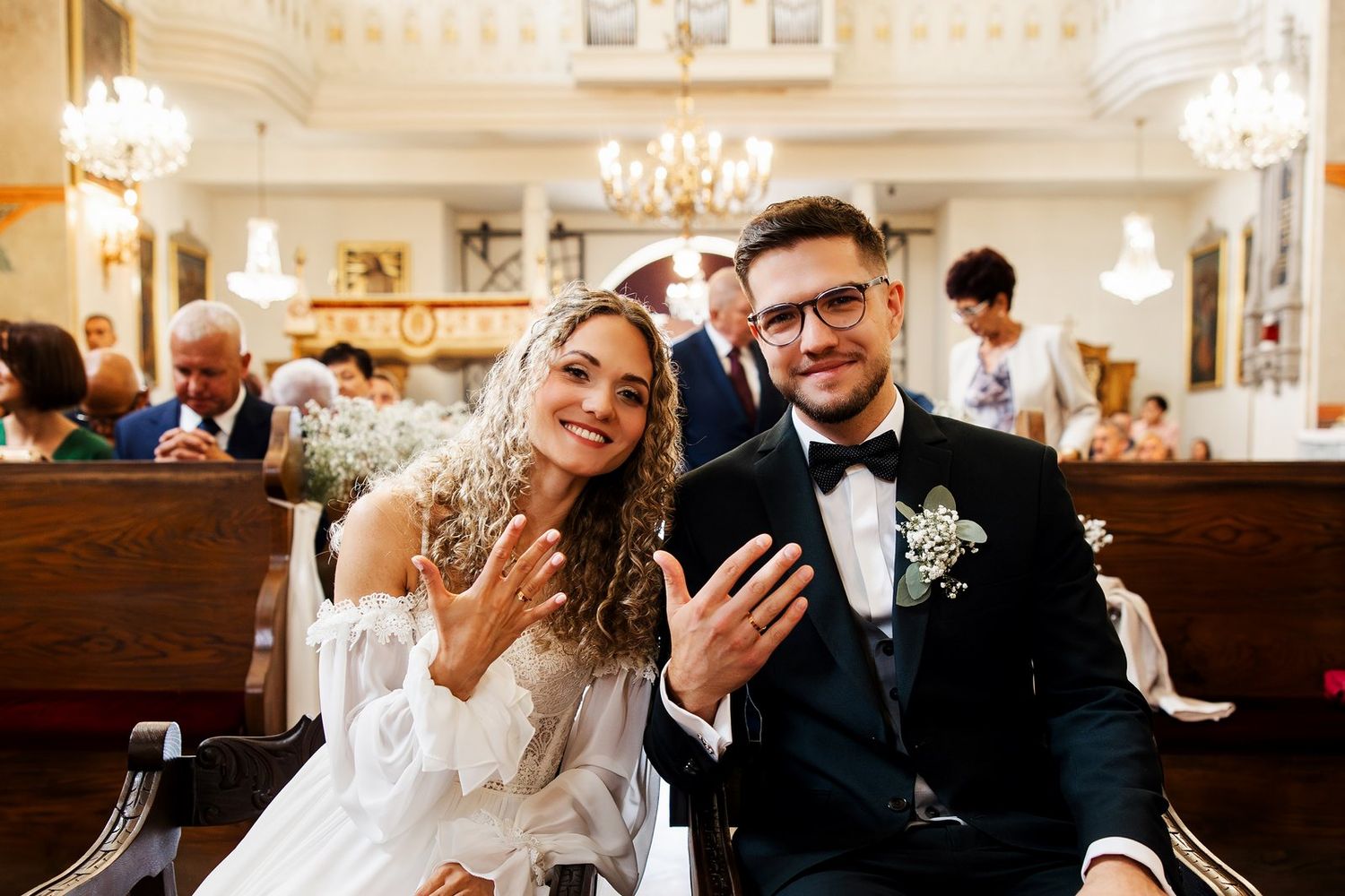 Para młoda pokazuje do obiektywu obrączki zaraz po ceremonii zaślubin
