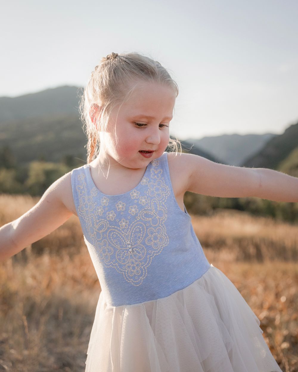 Dancing and twirling in a white lace dress against a mountain backdrop.