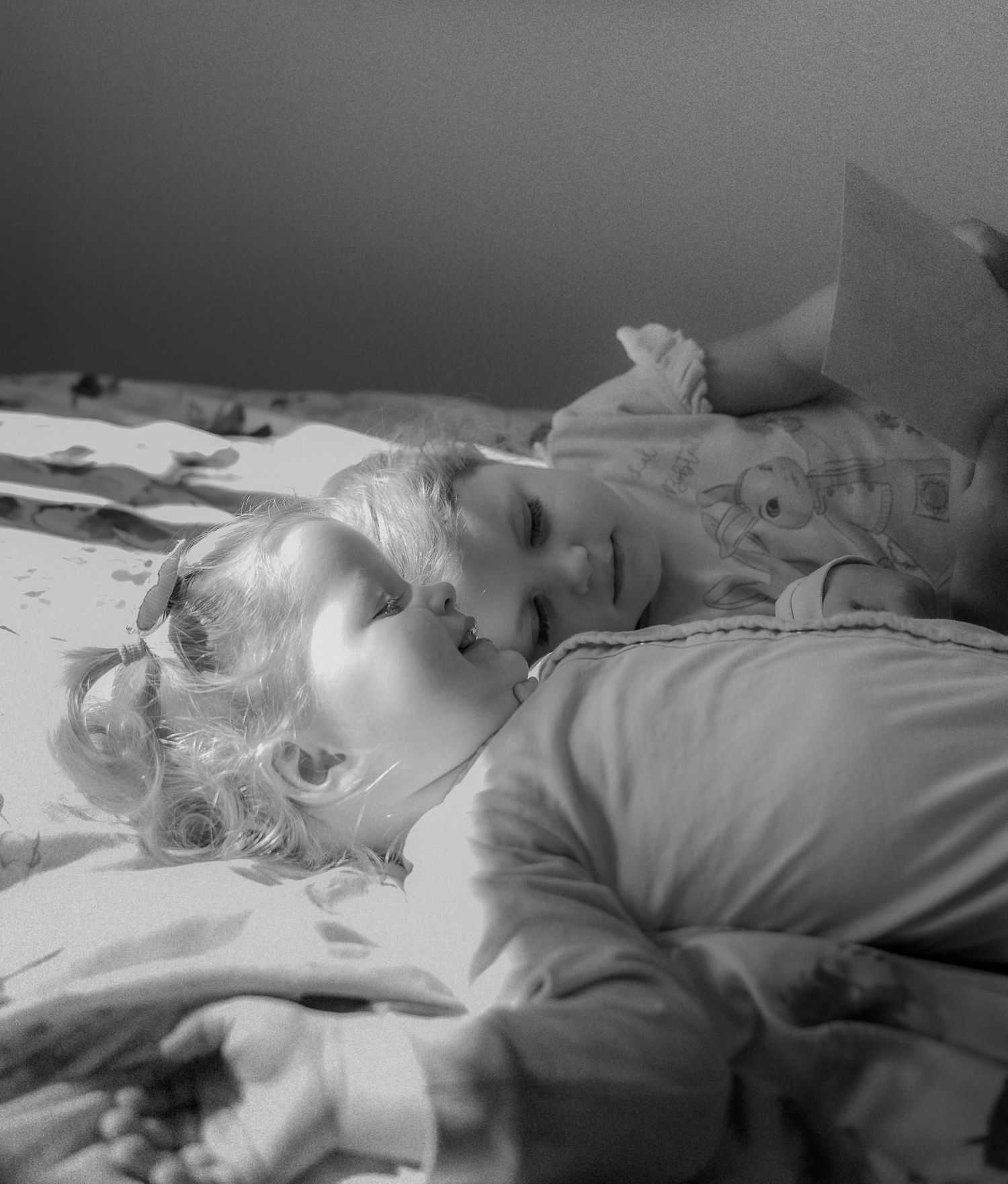 Children jumping on the bed in pyjamas during a relaxed storytelling photo session in Leicestershire.