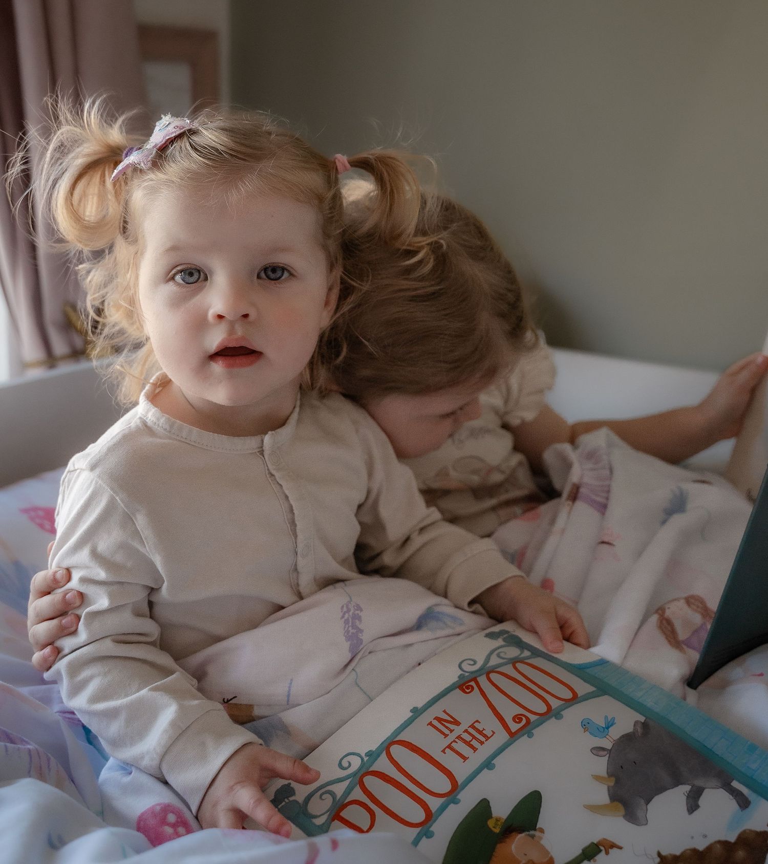 Close-up portrait of a young child in pyjamas looking up while cuddling sibling during an in-home family photography session in Derbyshire.
