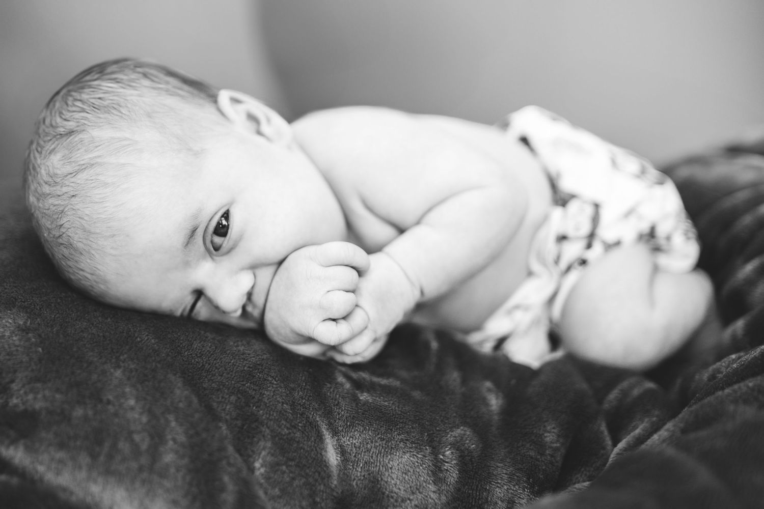 A dramatic black and white photo series capturing tender moments with a baby lying in different serene poses.