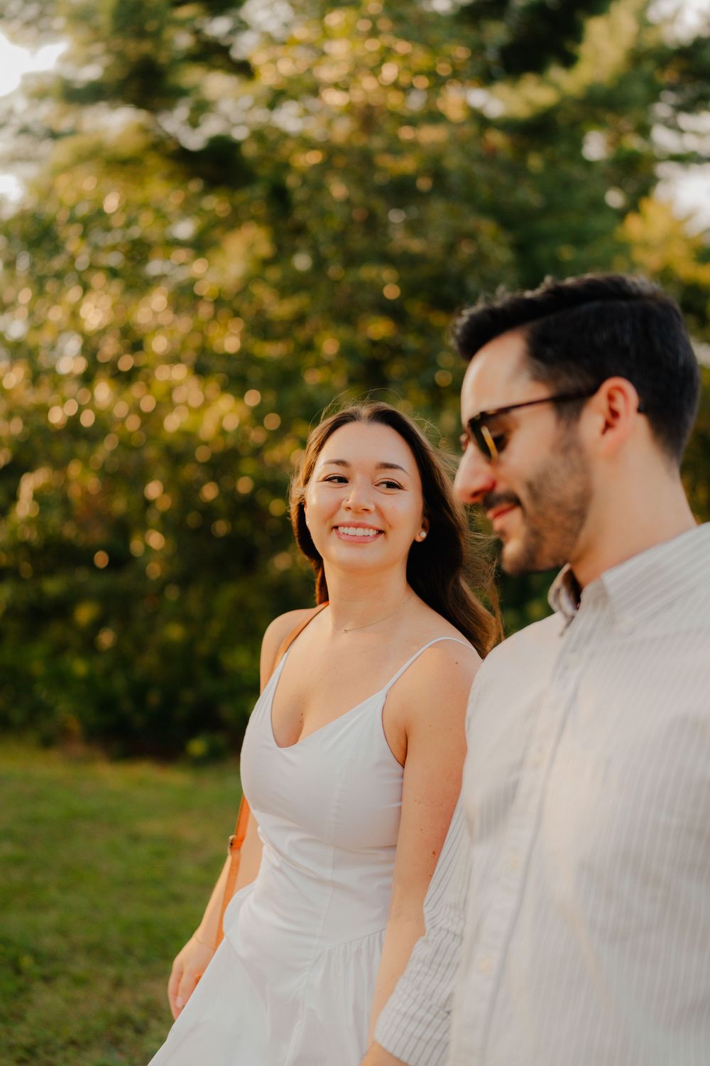 A couple shares joyful laughter while standing together outdoors during golden hour.