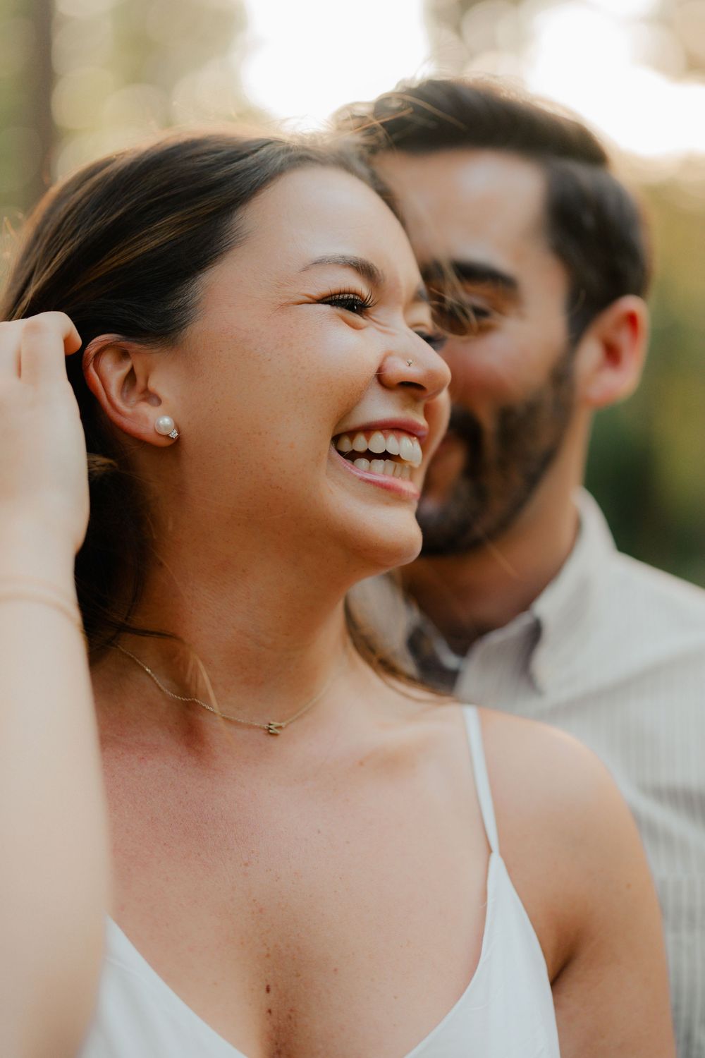 Close up shot of a joyful woman in elegant attire during golden hour at a celebratory event at sunset.
