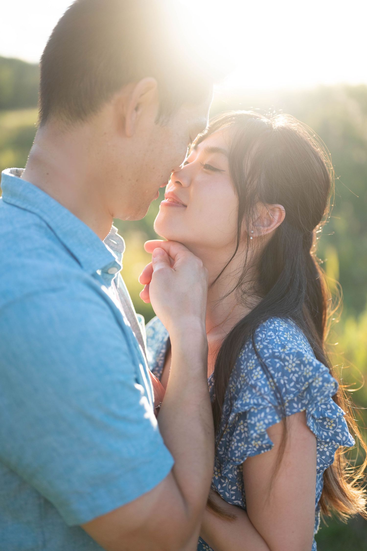 A romantic couple sharing an intimate moment in a sunlit field with golden hour lighting.