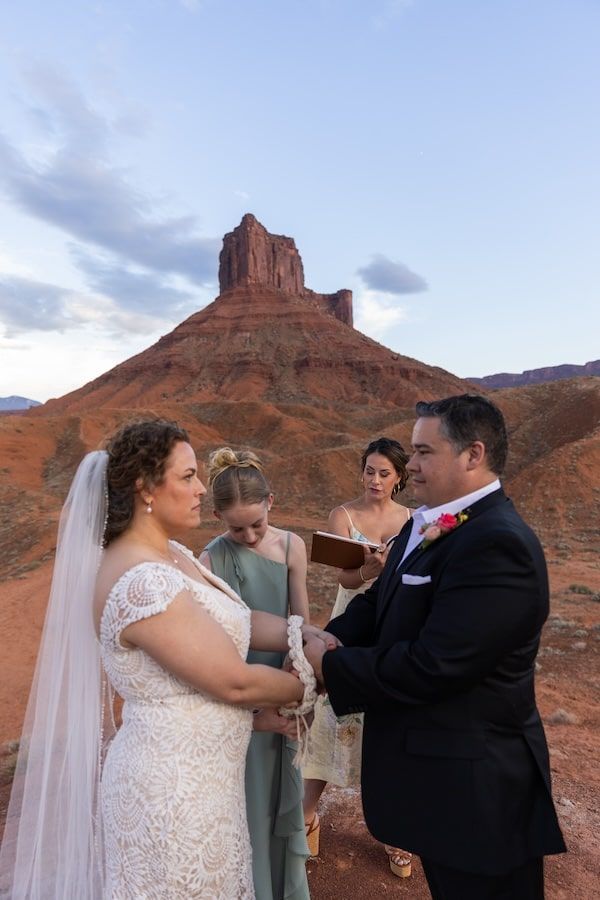 Wedding ceremony with dramatic red rock formations in Castle Valley, Utah during golden hour sunset.