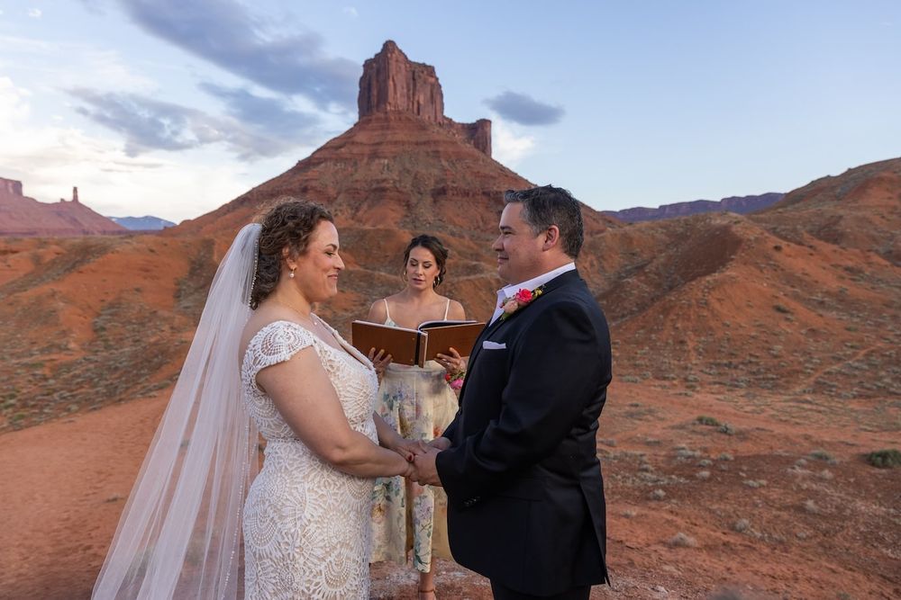 Wedding ceremony taking place at sunset in Monument Valley with towering red rock formations in the background.