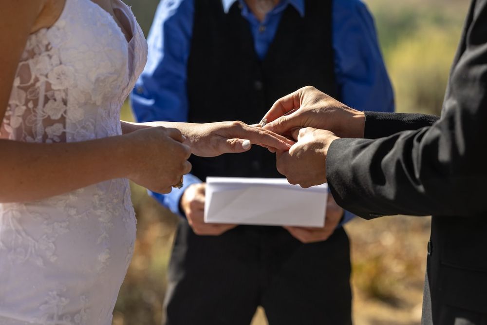 Professional exchanging documents and signing paperwork with someone in front of a sunny outdoor backdrop.