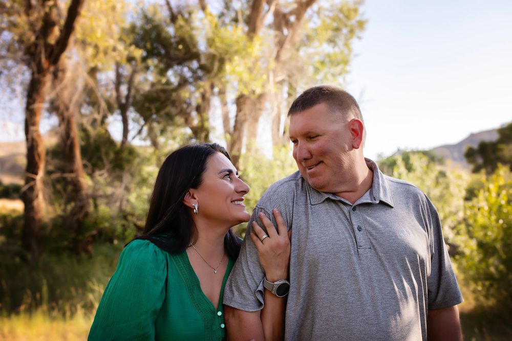 A couple shares a joyful moment together outdoors with trees in the background during golden hour.