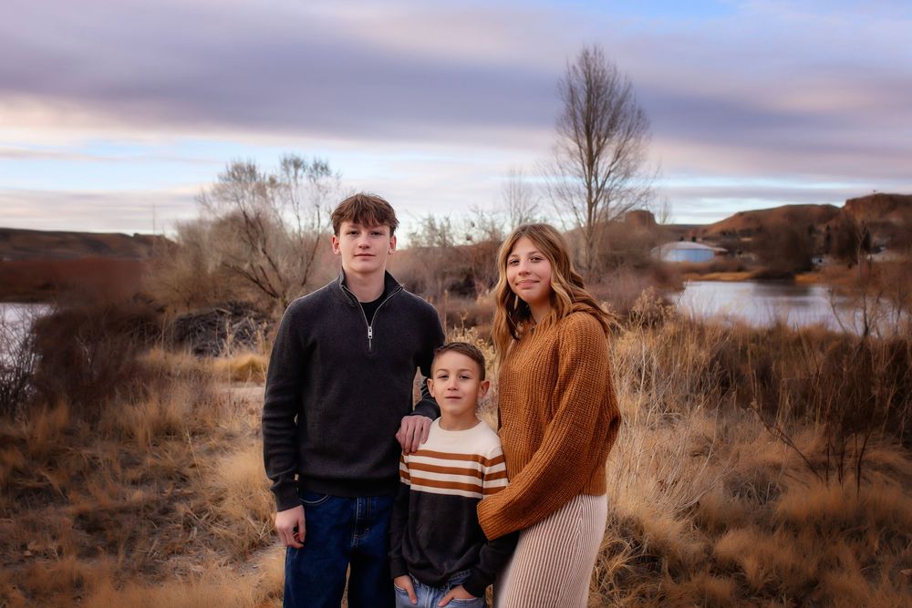 Family poses together in casual winter clothing against a desert landscape at sunset for outdoor portraits.