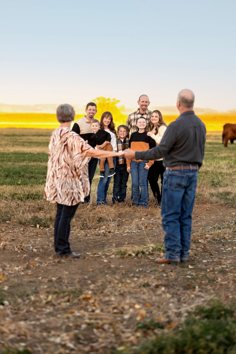 Group gathered on a rural field during golden hour with chairs creating a relaxed outdoor setting in autumn.