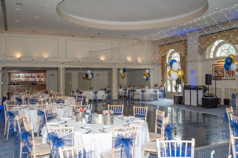 Wedding reception hall decorated in white and blue with chiavari chairs and round tables.