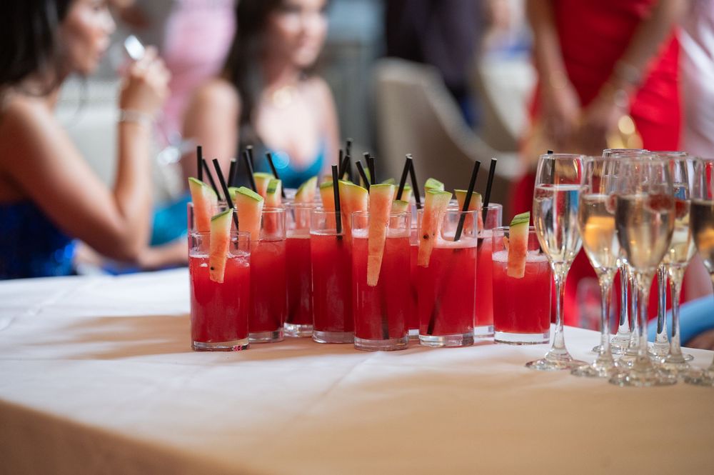 Row of colorful cocktails lined up on a bar at a formal event.