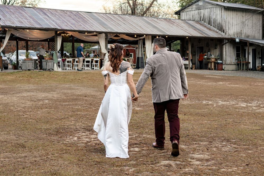 bride and groom walking away towards a barn
