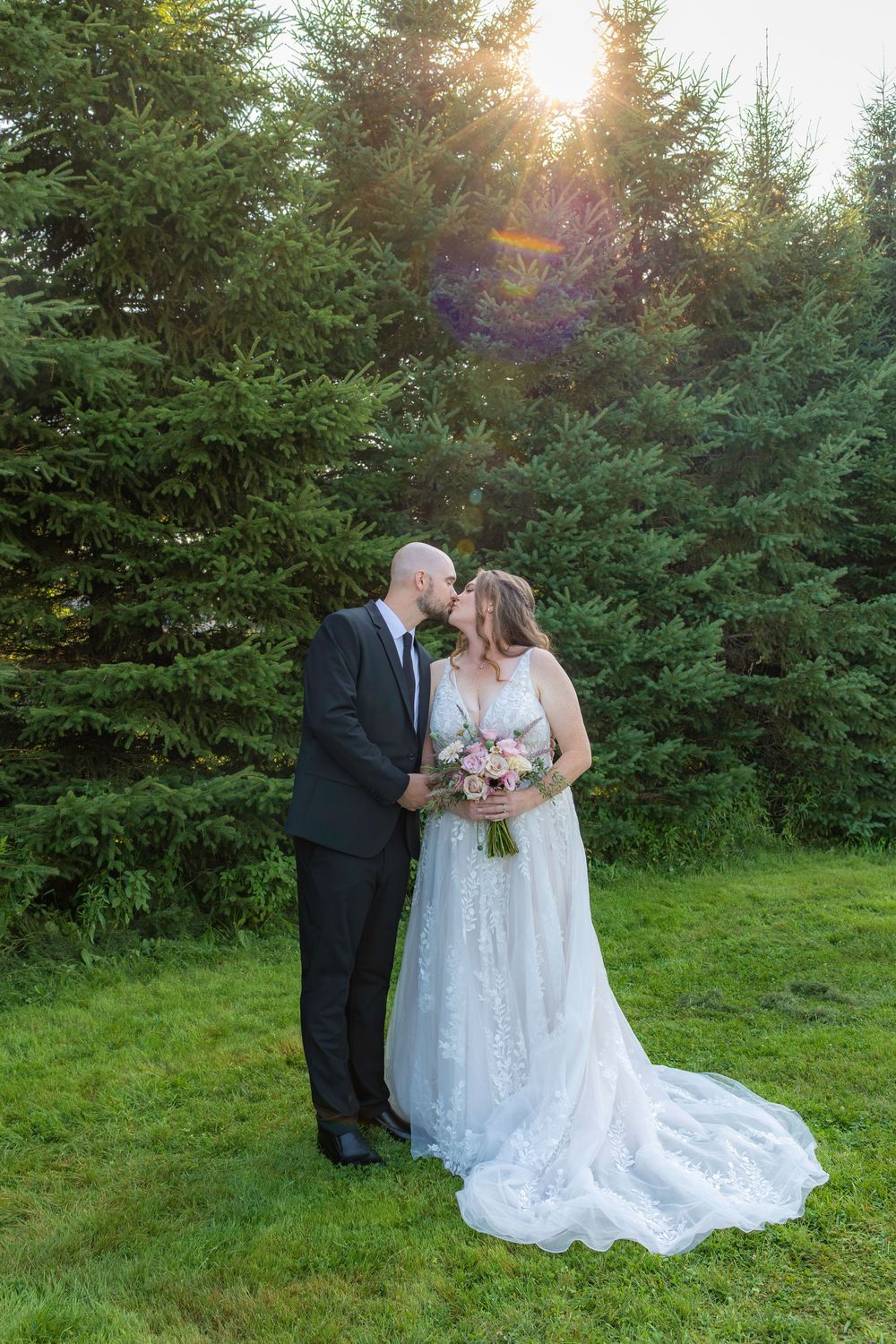 A romantic sunset wedding moment captured in a lush green garden setting with soft golden light filtering through trees.