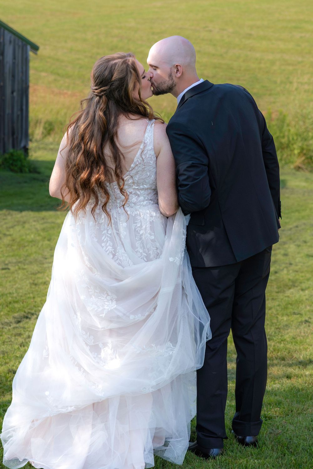 Romantic outdoor wedding sequence showing newlyweds sharing tender moments in a grassy field.