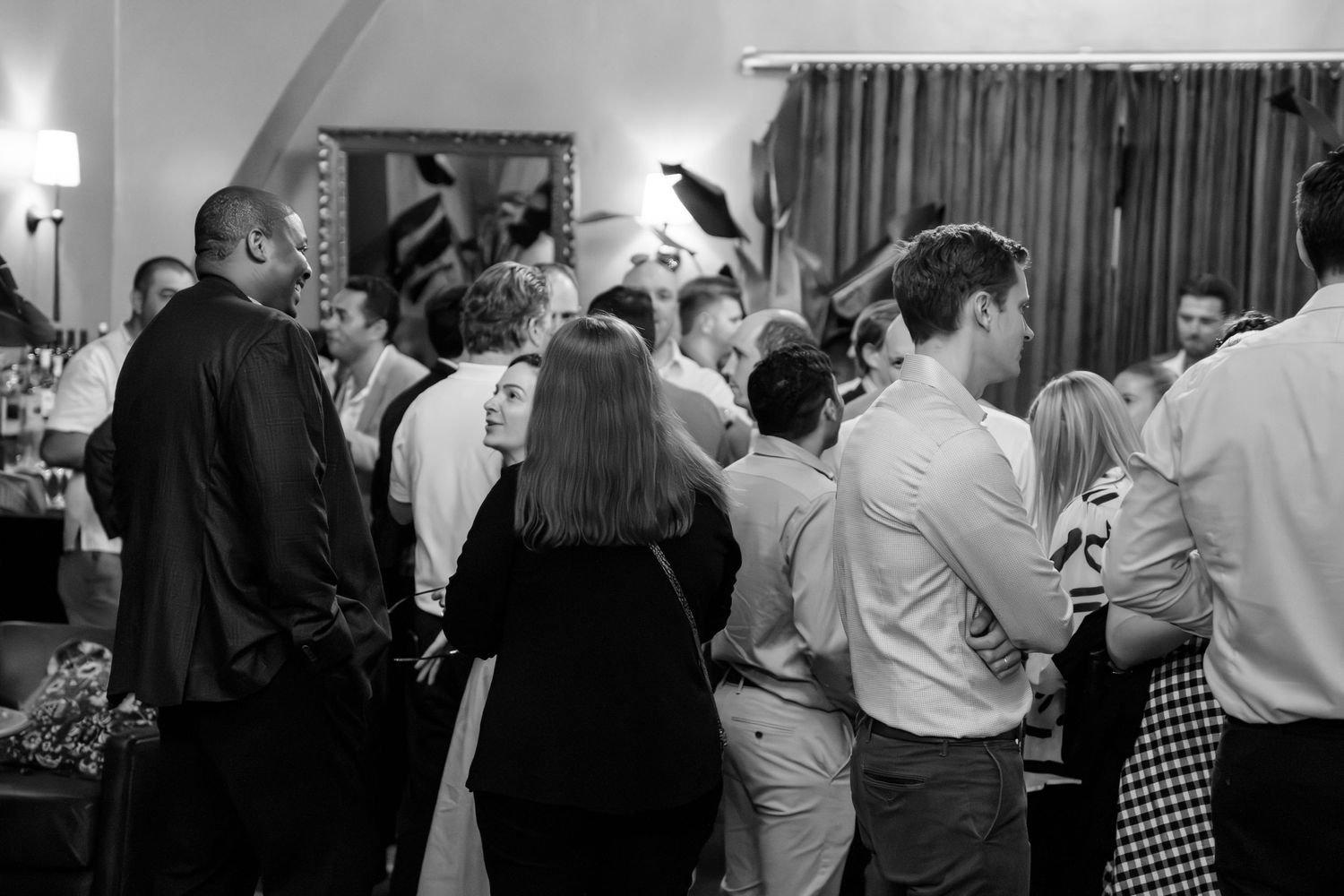 Guests mingling at an elegant indoor social event in black and white photography.