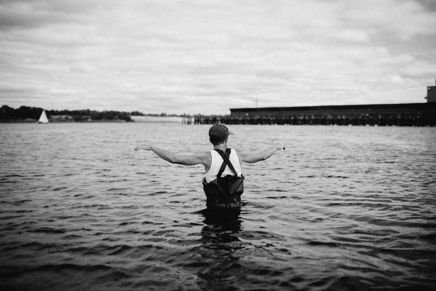 Artist Eli Nixon wading into the Providence River in black and white photograph for Providence Commemoration Lab by Rachel Maeve