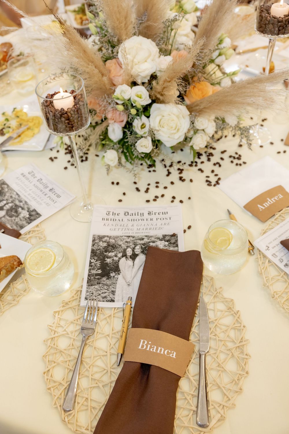 Elegant bridal shower table setting with floral centerpiece, brown napkin, and coffee sleeve place cards.