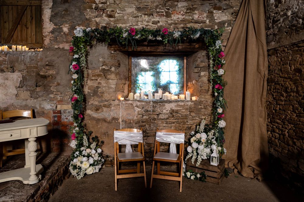 Flower arch and two chairs for the Bride and Groom in the rustic chapel at Ash Barton Estate.