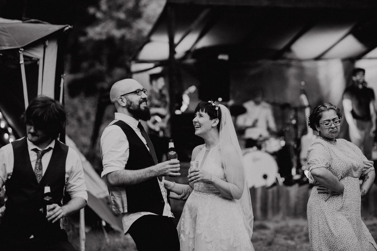 Bride and groom share a romantic kiss under a lush green archway in a garden wedding setting.
