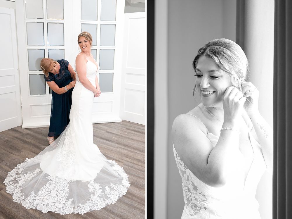 Bride smiling while putting on earrings and mother helping zip up elegant lace wedding gown.