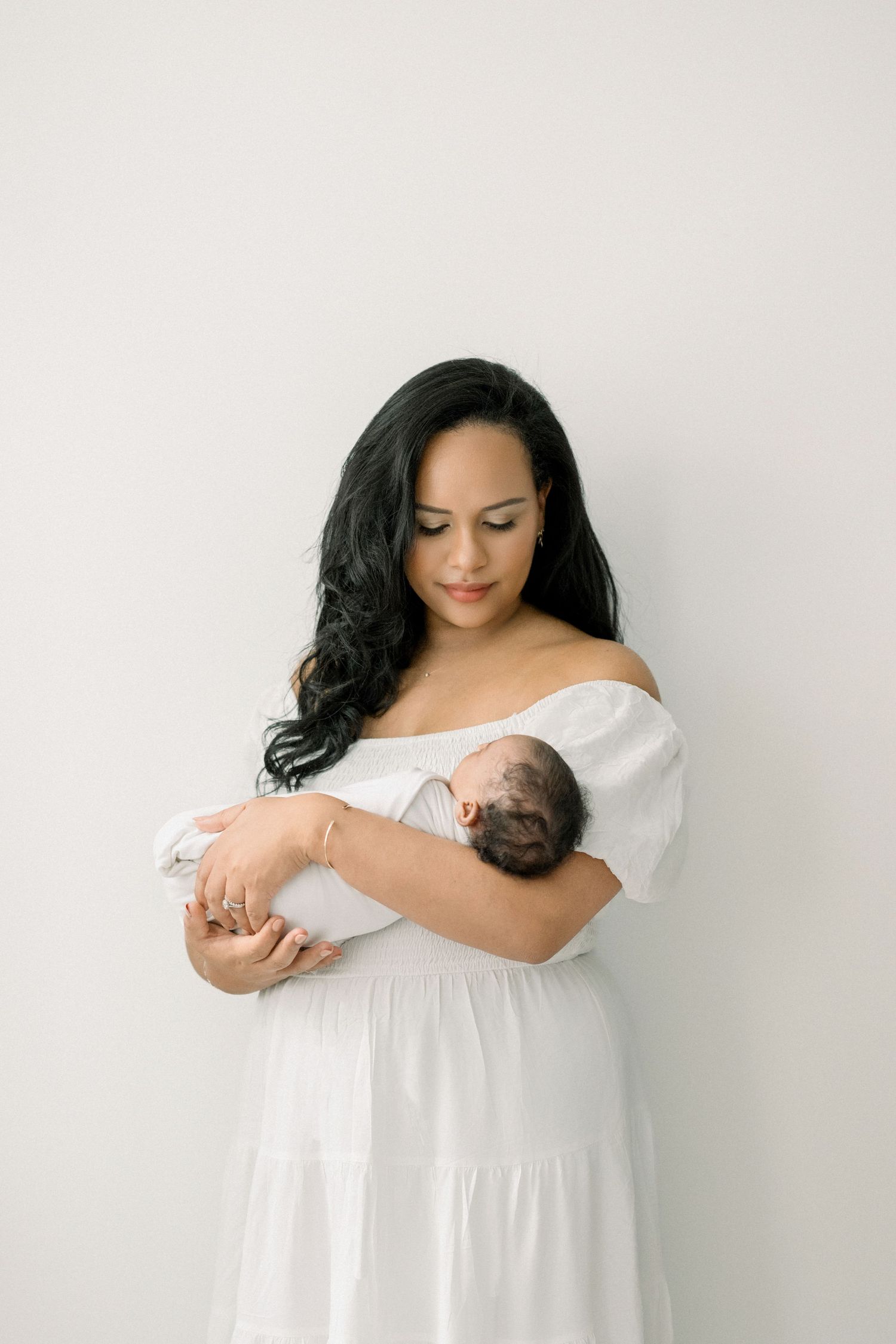 mother holding baby in a neutral outfit at a washington dc newborn session in-home