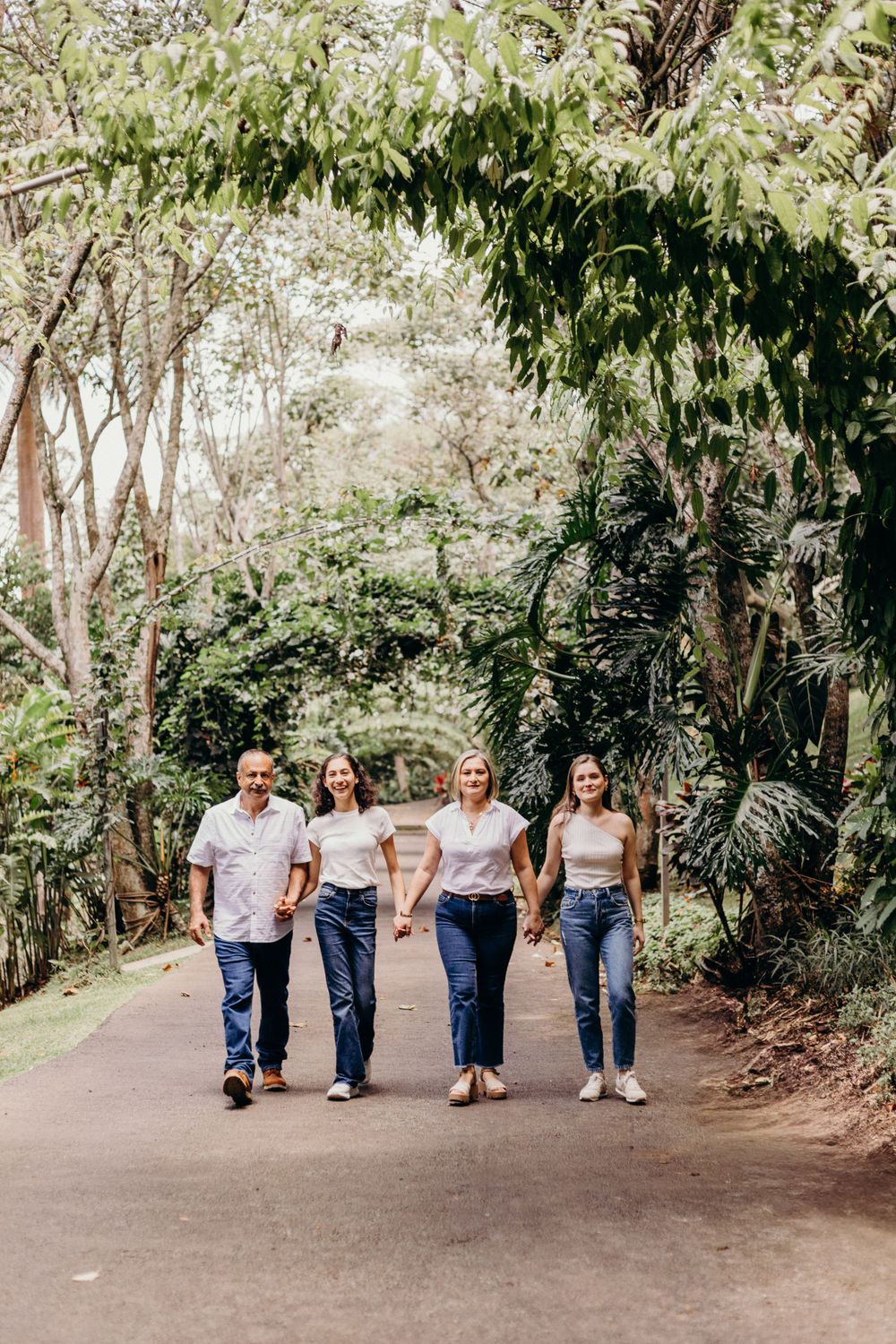 Group walking together on a tree-lined path wearing coordinated white shirts and jeans.