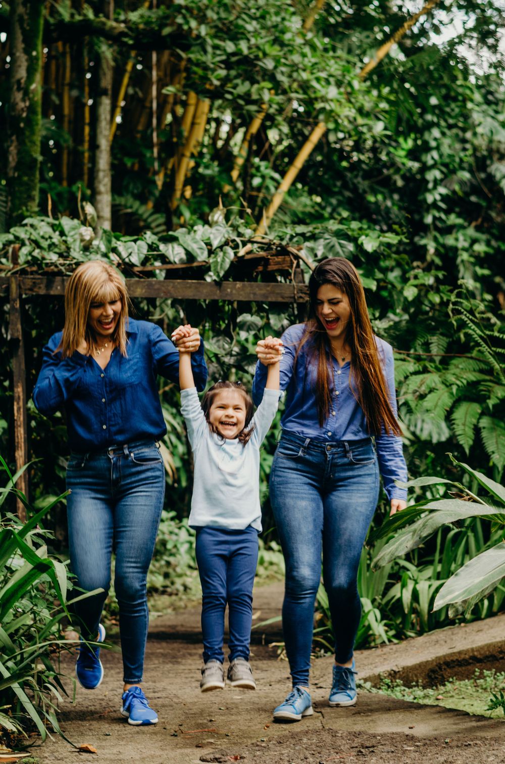 Family walking together on a nature path surrounded by lush tropical plants.