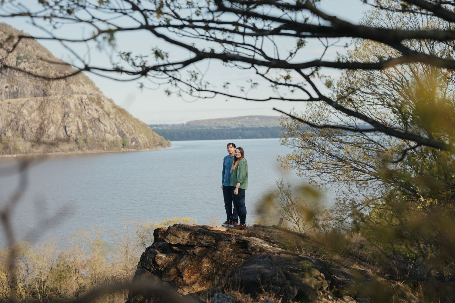 Couple sharing a romantic kiss at a scenic mountain overlook with dramatic cloudy skies and valley views.