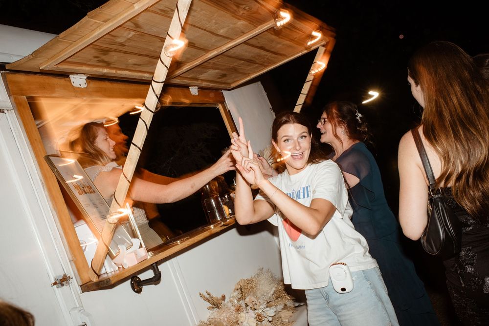 Young woman high-fiving through a wooden food truck window at a nighttime outdoor event.