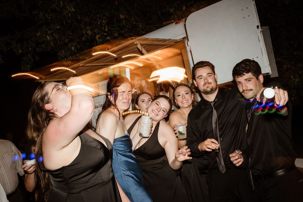 Group of young adults posing together at a formal evening outdoor event, dressed in elegant attire.