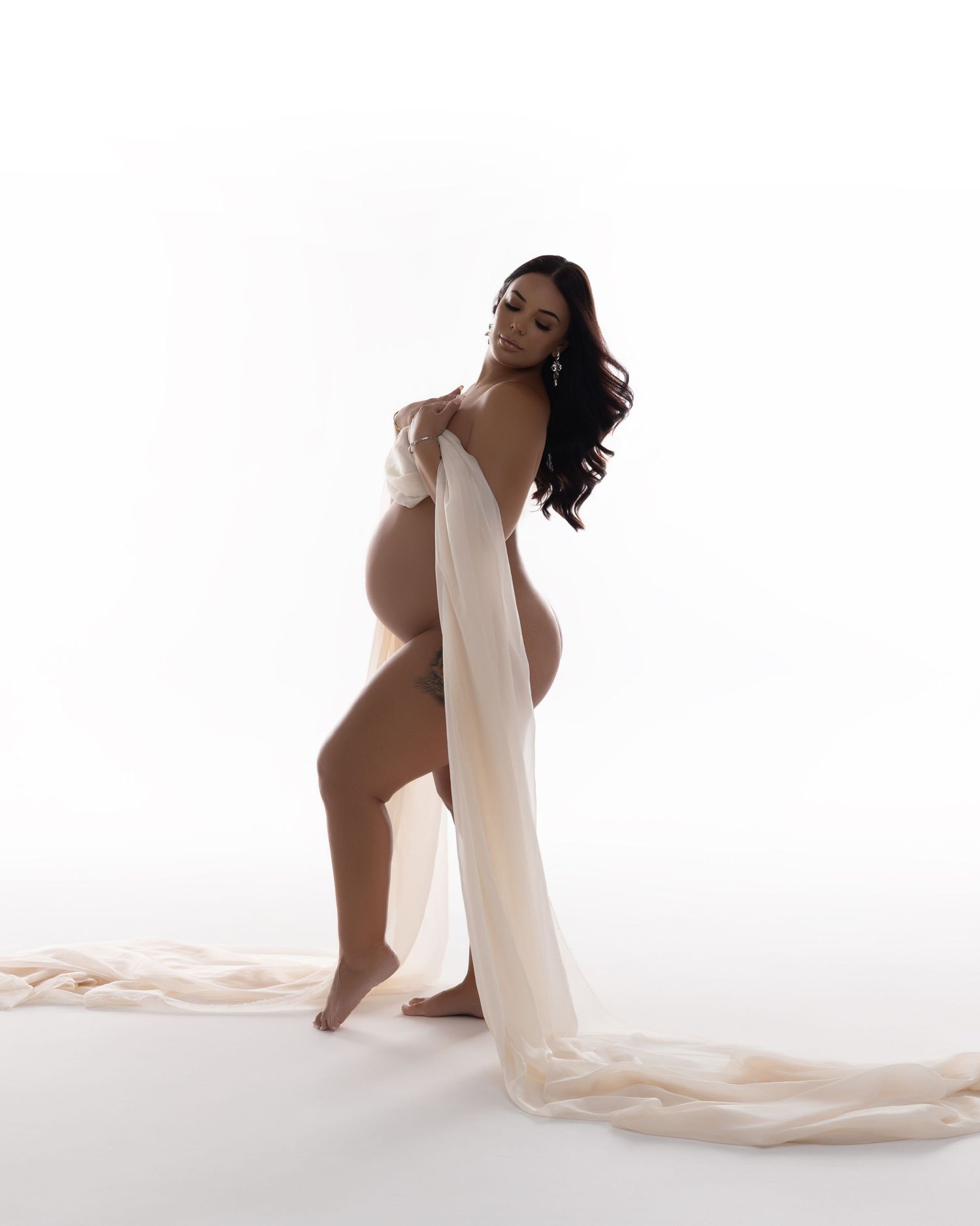 Black and white maternity photo emphasizing pregnancy curves with minimalist styling.