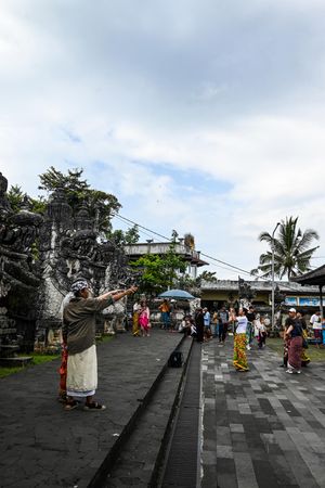 Balinese worshippers in traditional attire performing a ritual ceremony at an ornate Hindu temple courtyard in Bali.
