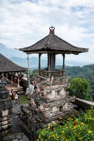 Ancient Balinese Hindu temple pagoda with traditional tiered roof overlooking lush green mountain valley in Bali.