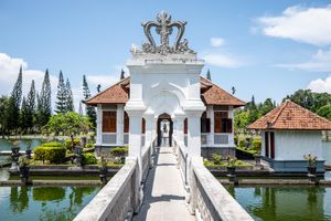 Ornate white gateway bridge over a serene pond at Taman Ujung Water Palace in Bali, Indonesia.