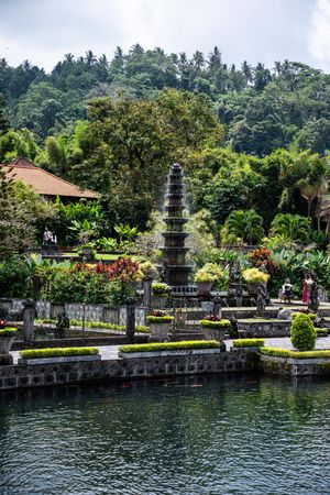Tiered stone fountain surrounded by tropical gardens and a reflective pool at Tirta Gangga Water Palace, Bali.