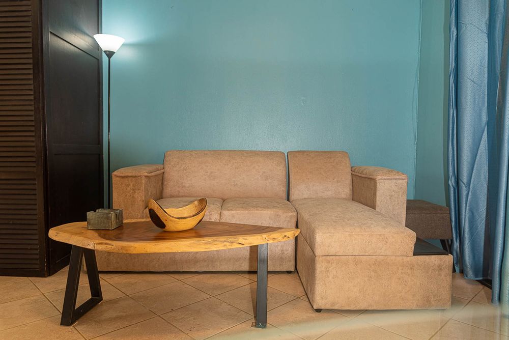 Modern living room with beige sectional sofa, round wood coffee table, and teal blue accent wall.