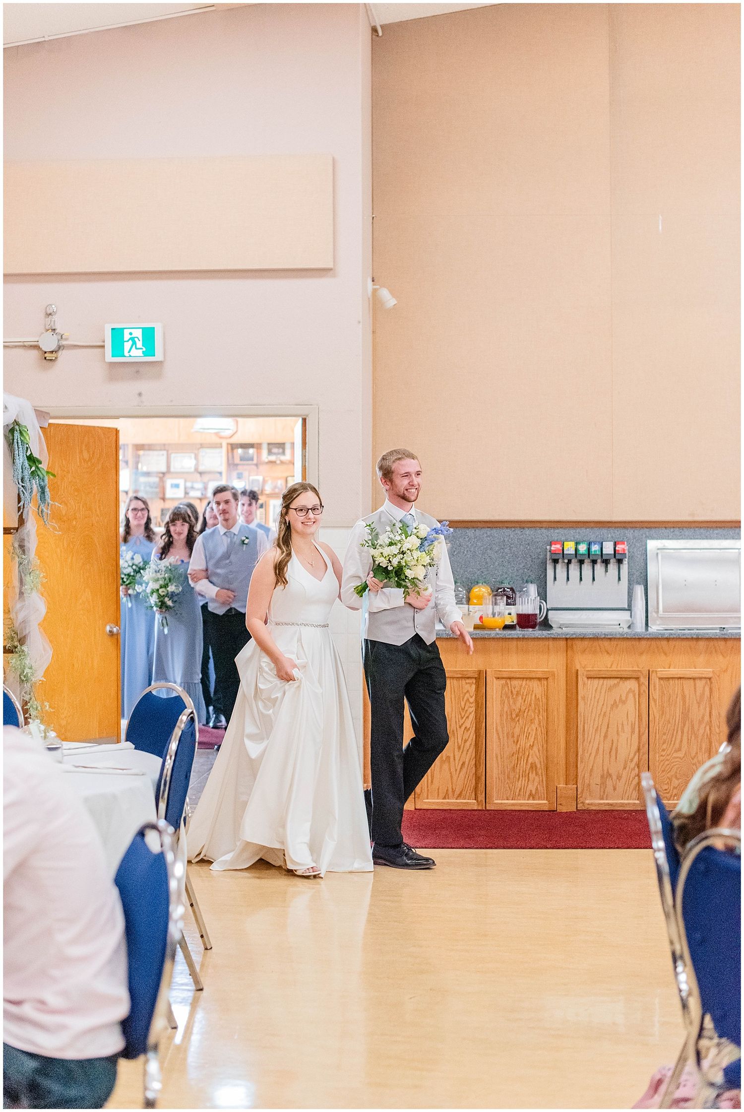 Bride and groom make grand entrance into wedding reception hall holding bouquet.