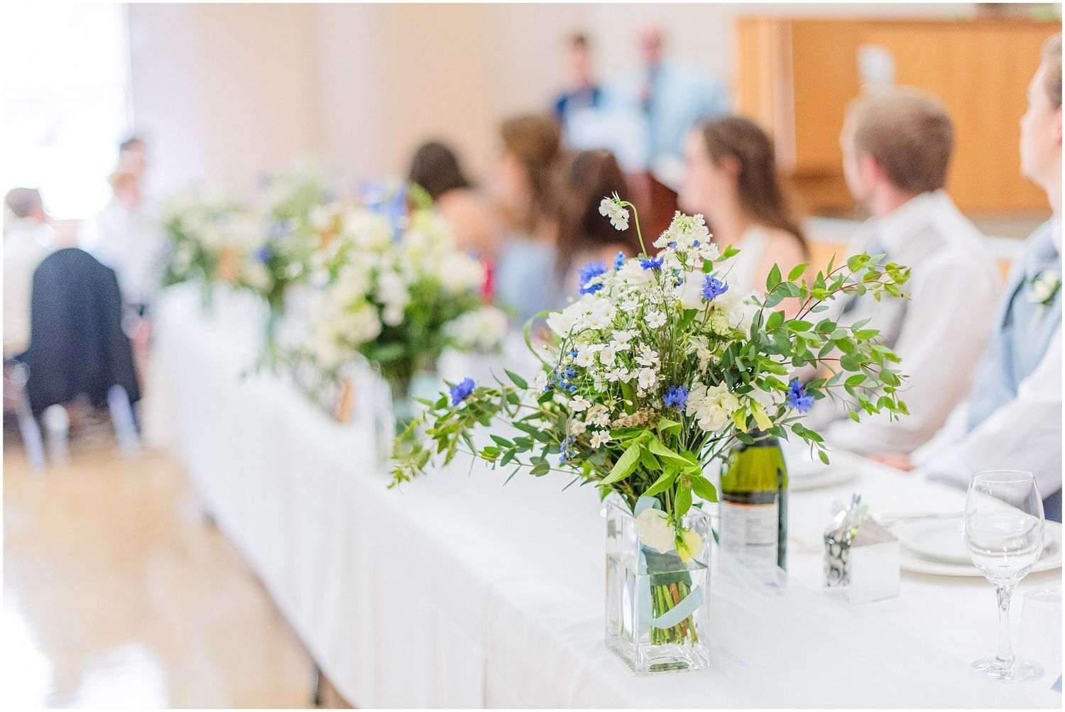 Elegant wedding reception table adorned with rustic mason jar floral arrangements of white and blue blooms.