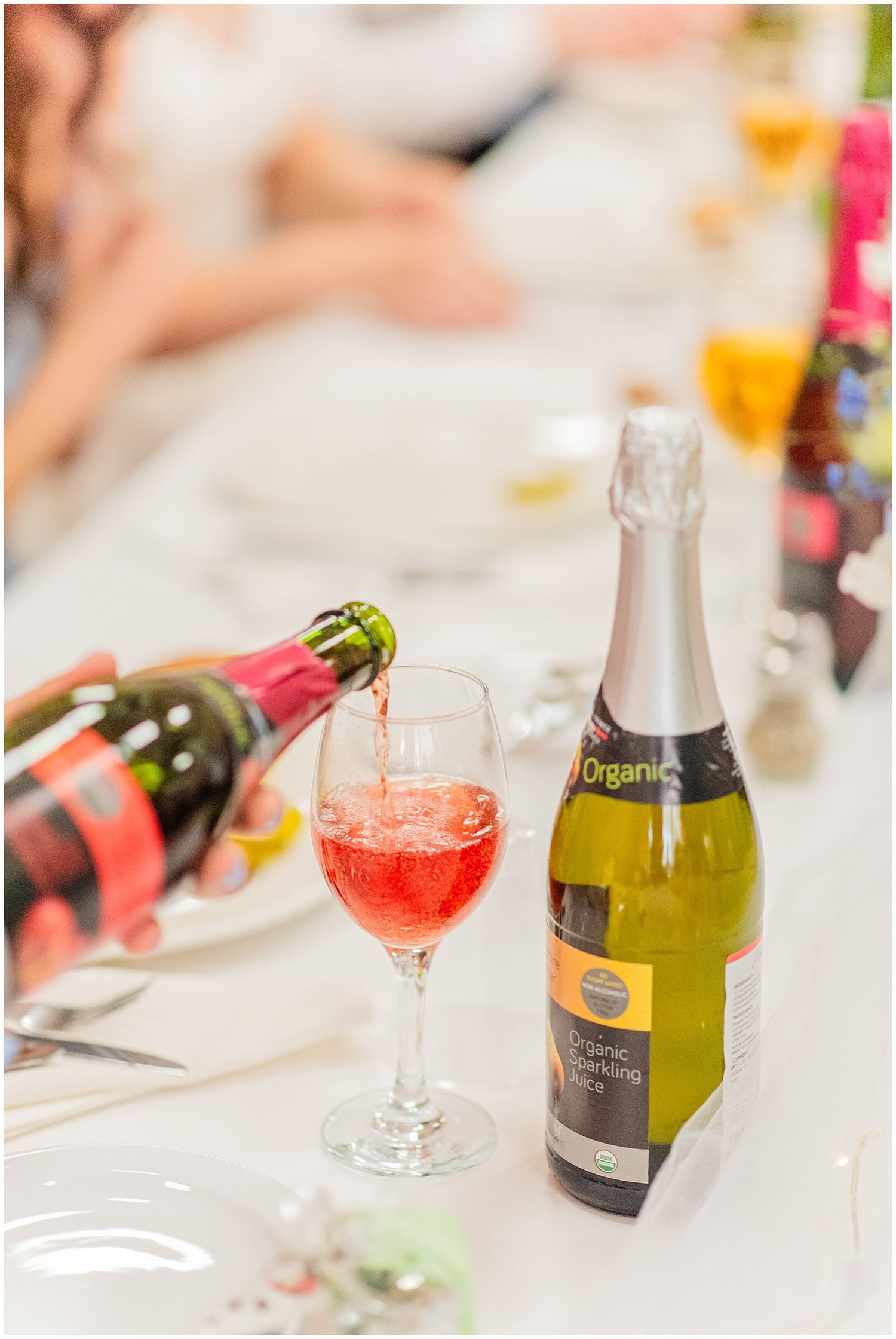 Organic sparkling wine being poured into a glass at an elegant wedding reception table setting.